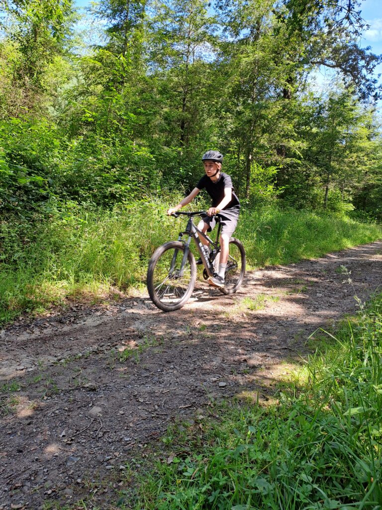 Leerling fietst over een bospad tijdens een actieve schoolreis.